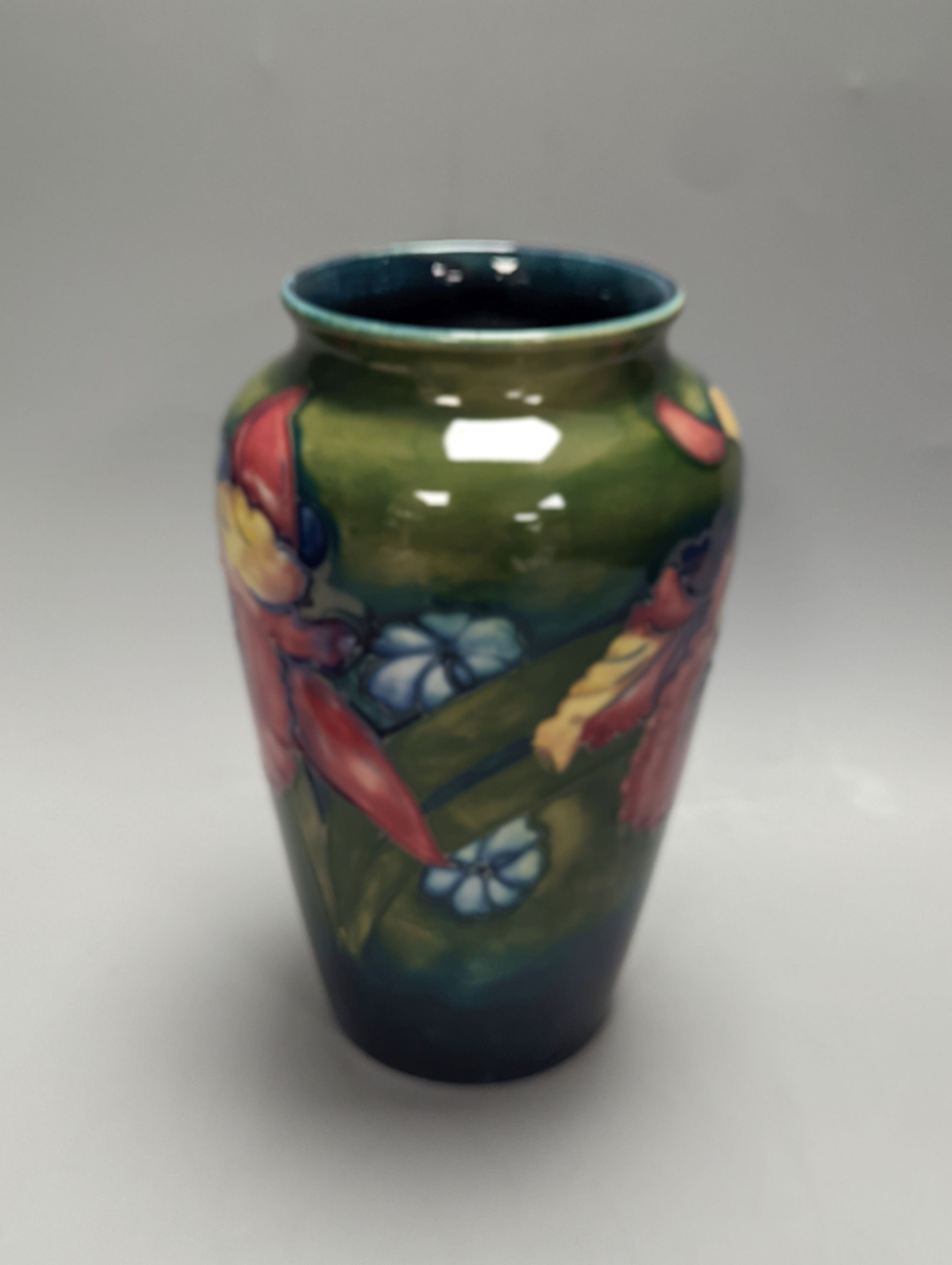 A Moorcroft orchid pattern green glazed vase, signed William Moorcroft to underside and a similar maroon dish, initialled ‘BM’ and M.C.C 286 to underside, 21cm